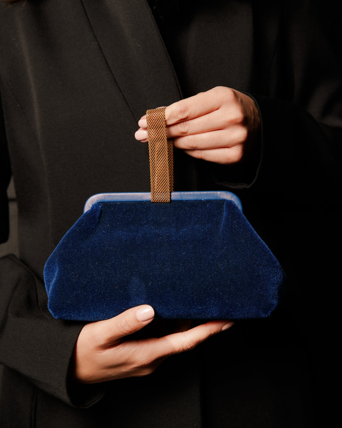 Blue clutch held by a person wearing a black coat